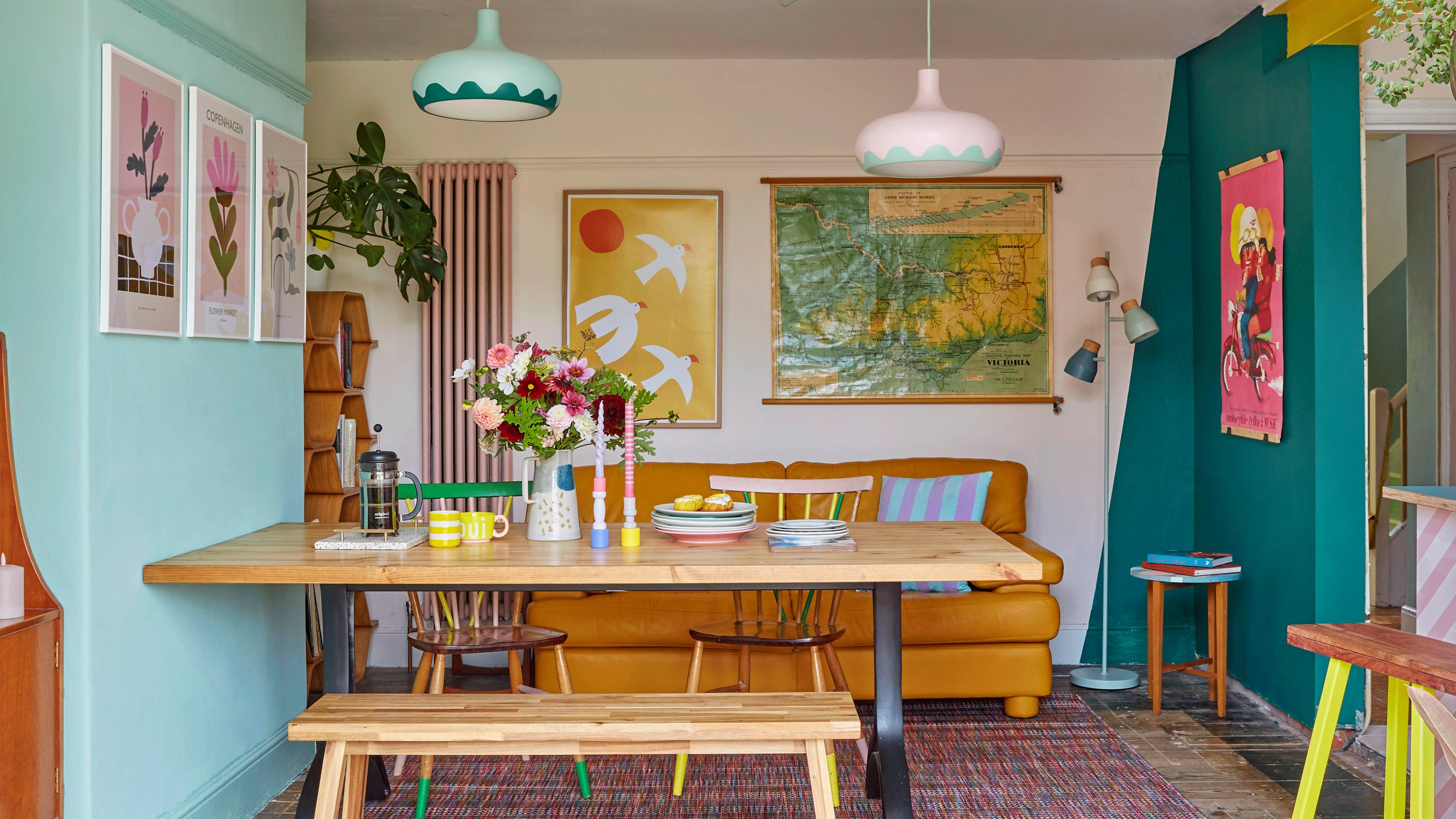 Colourful dining area with wooden table and bench and mustard yellow sofa