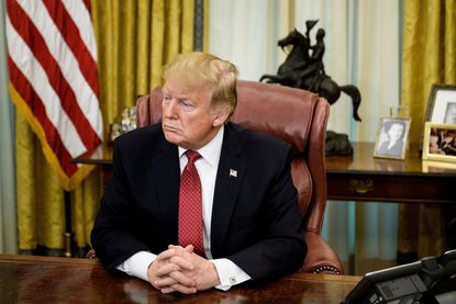 Trump sits at his empty Oval Office desk