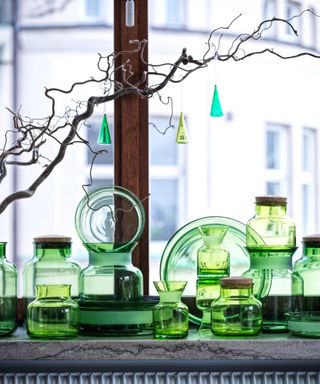 Green glass jars and glass Christmas ornaments in window