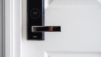 The best smart locks: Image depicts white door with black smart lock handle 