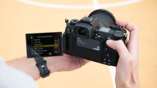 Nikon Z6 III camera held in a pair of hands with the vari-angle screen extended