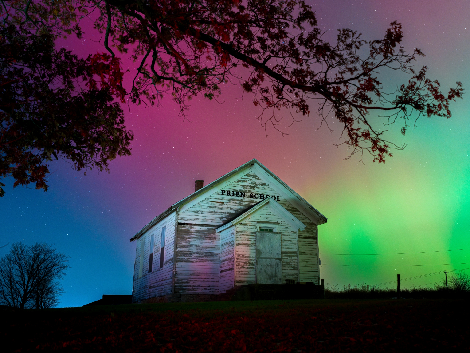 A photo of northern lights over an old school in Wisconsin farmland.