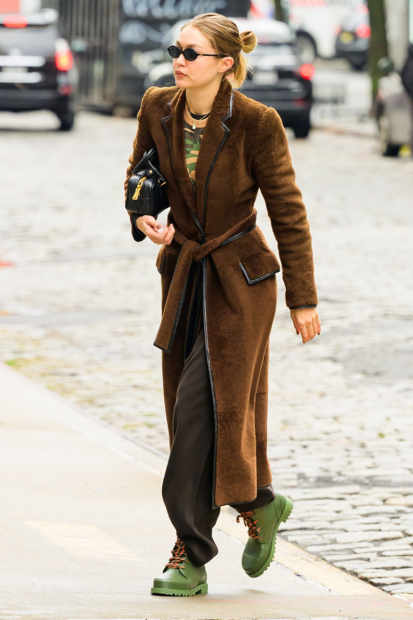 Gigi Hadid wearing a brown coat, brown pants, and green boots.