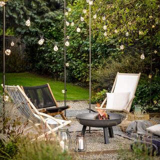 seating around a fire pit in garden, festoon lights, cushions and throws