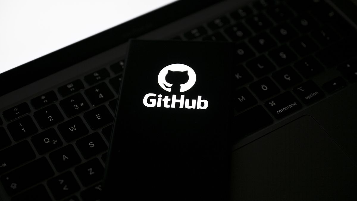 GitHub logo and branding displayed on a smartphone screen placed on top of a laptop keyboard.