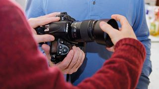 The lens hood being placed onto the lens of a Nikon DSLR camera