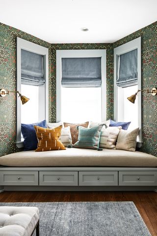 Built in window seat with green wallpaper and yellow and blue cushions