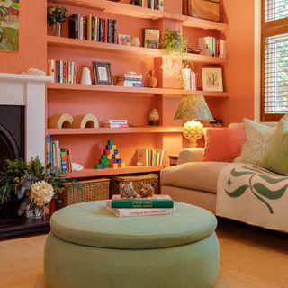 Warm toned living room colour scheme with greens and orange-pinks, pouffes, sofa, and shelving