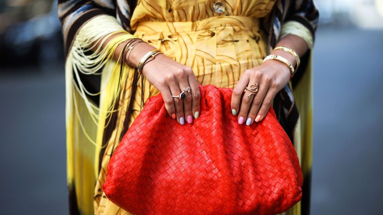 model with spring nail colors against a red handbag
