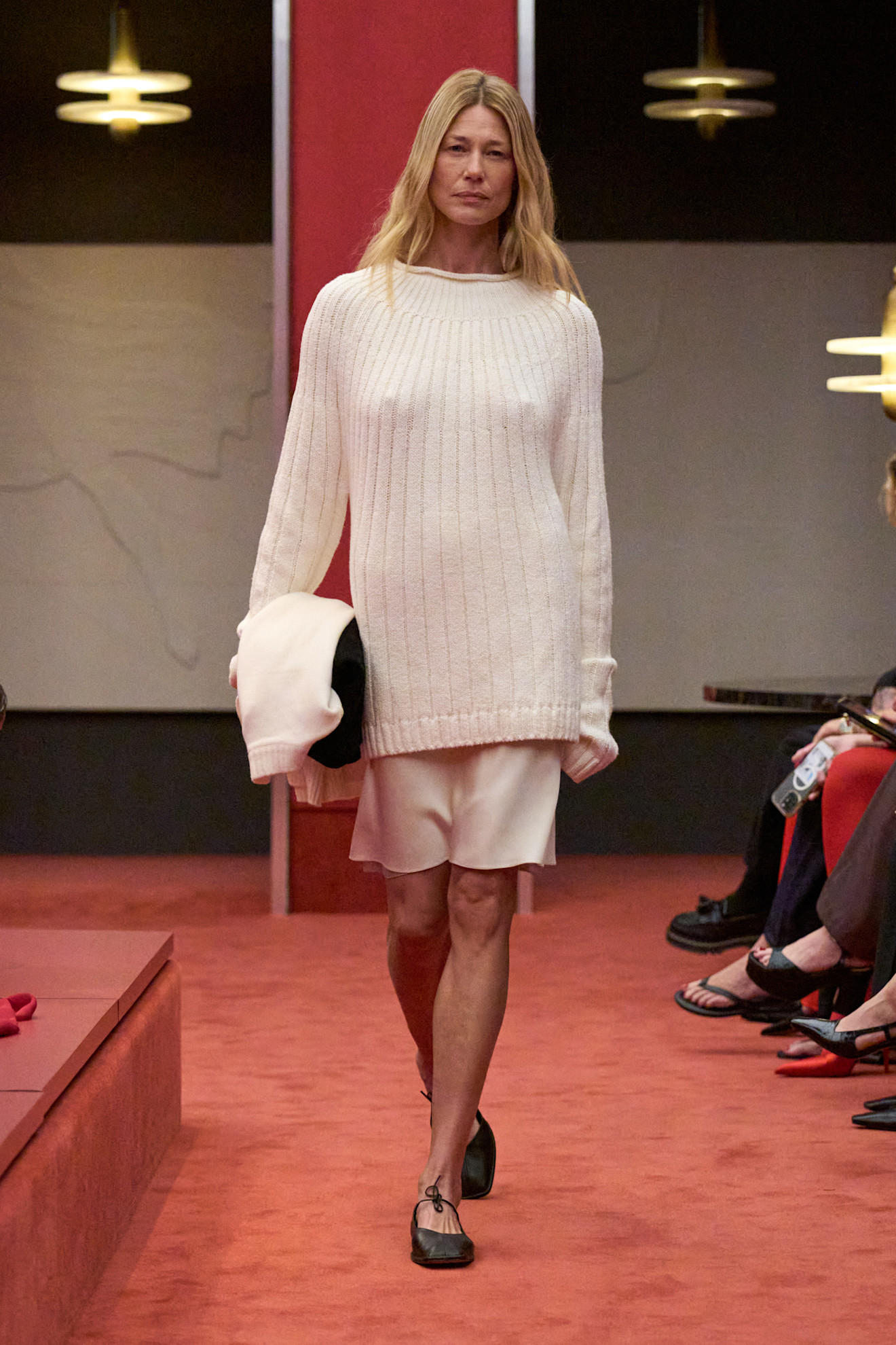 A model at the Kallmeyer show during S/S 25 fashion week wearing a loose-knit cotton sweater with a silk skirt and flats.