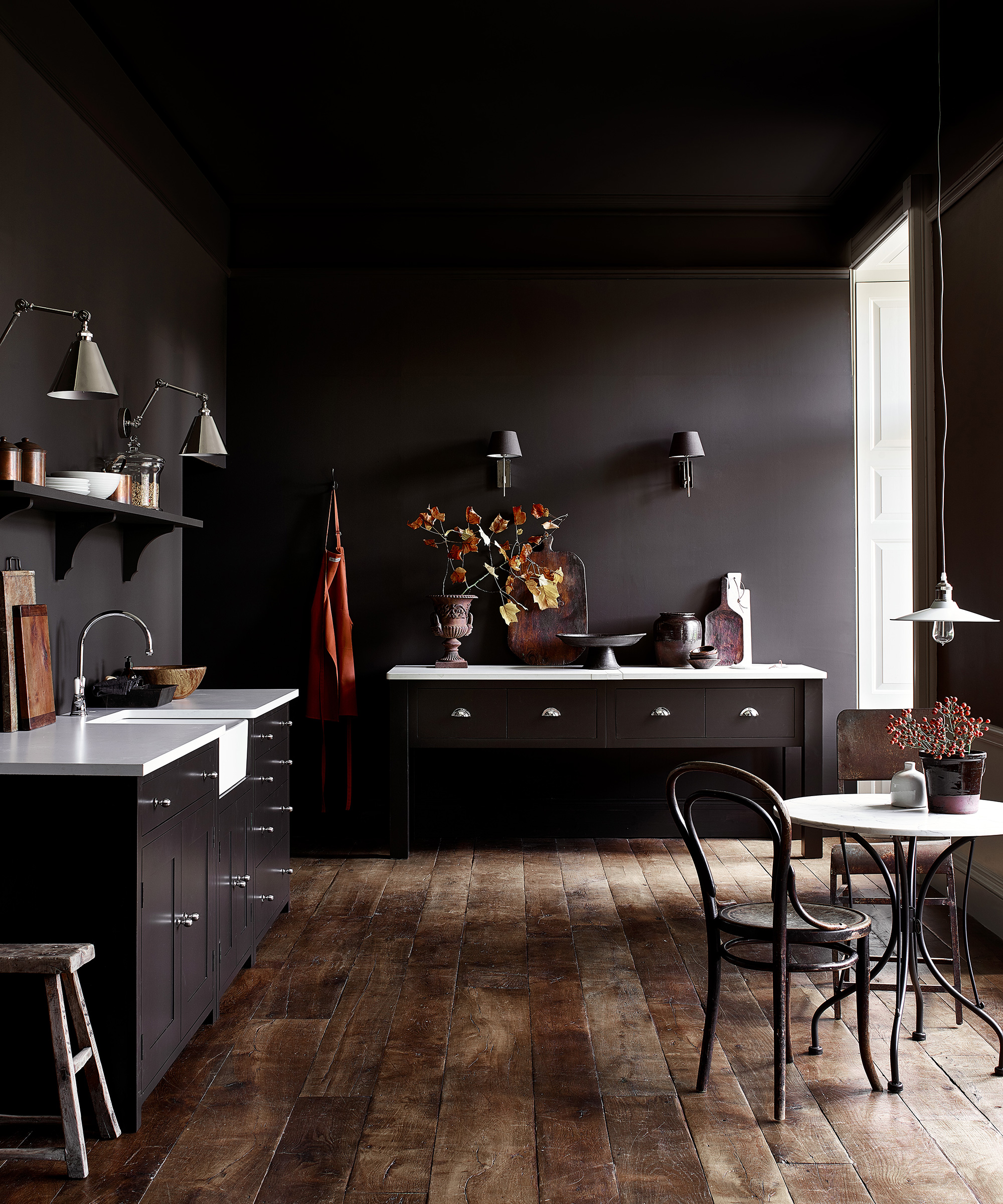 Kitchen design trends showing black walls and cabinets paired with a white worktop and textured wood flooring