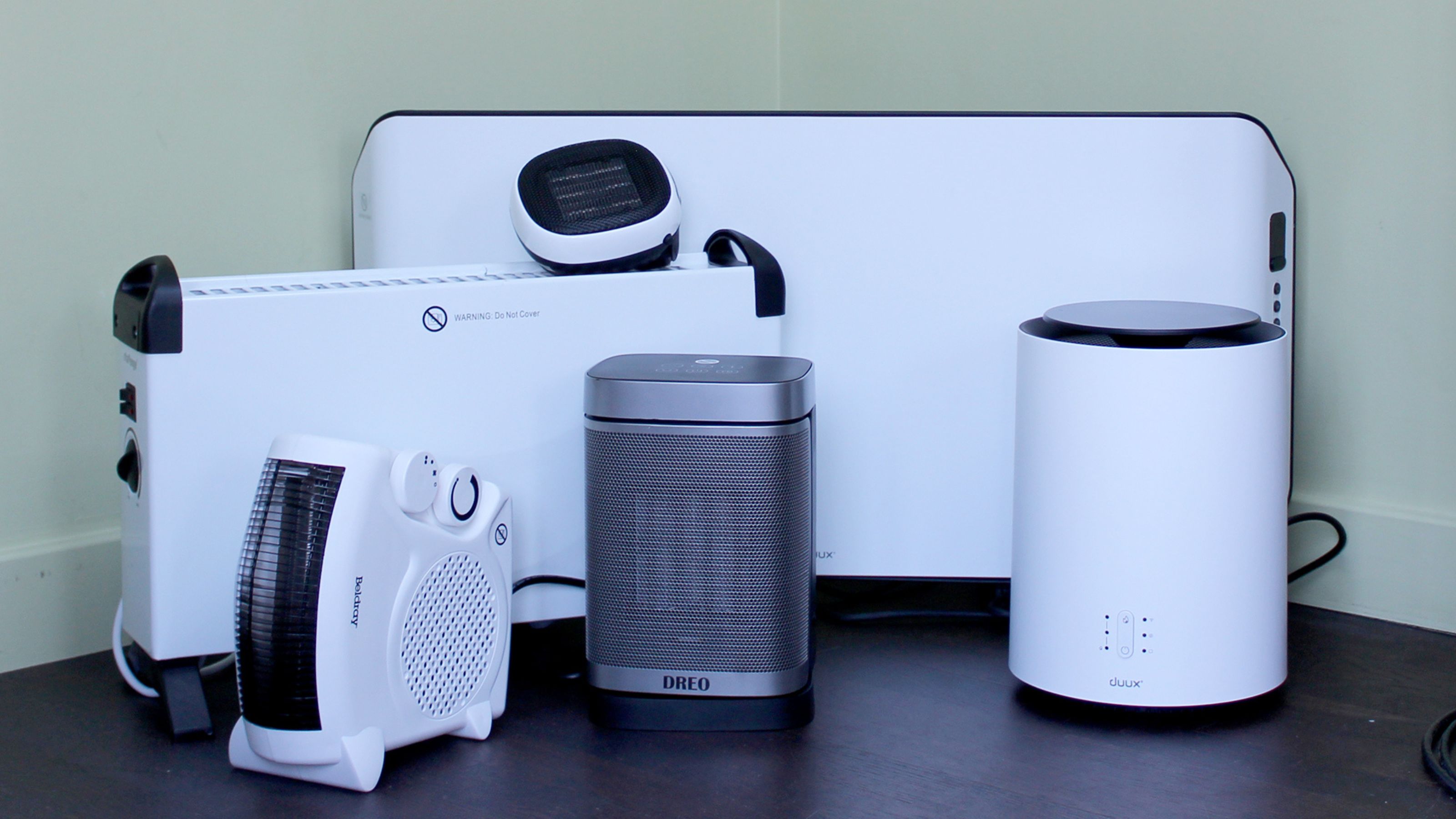 different electric heaters standing next to each other on black flooring
