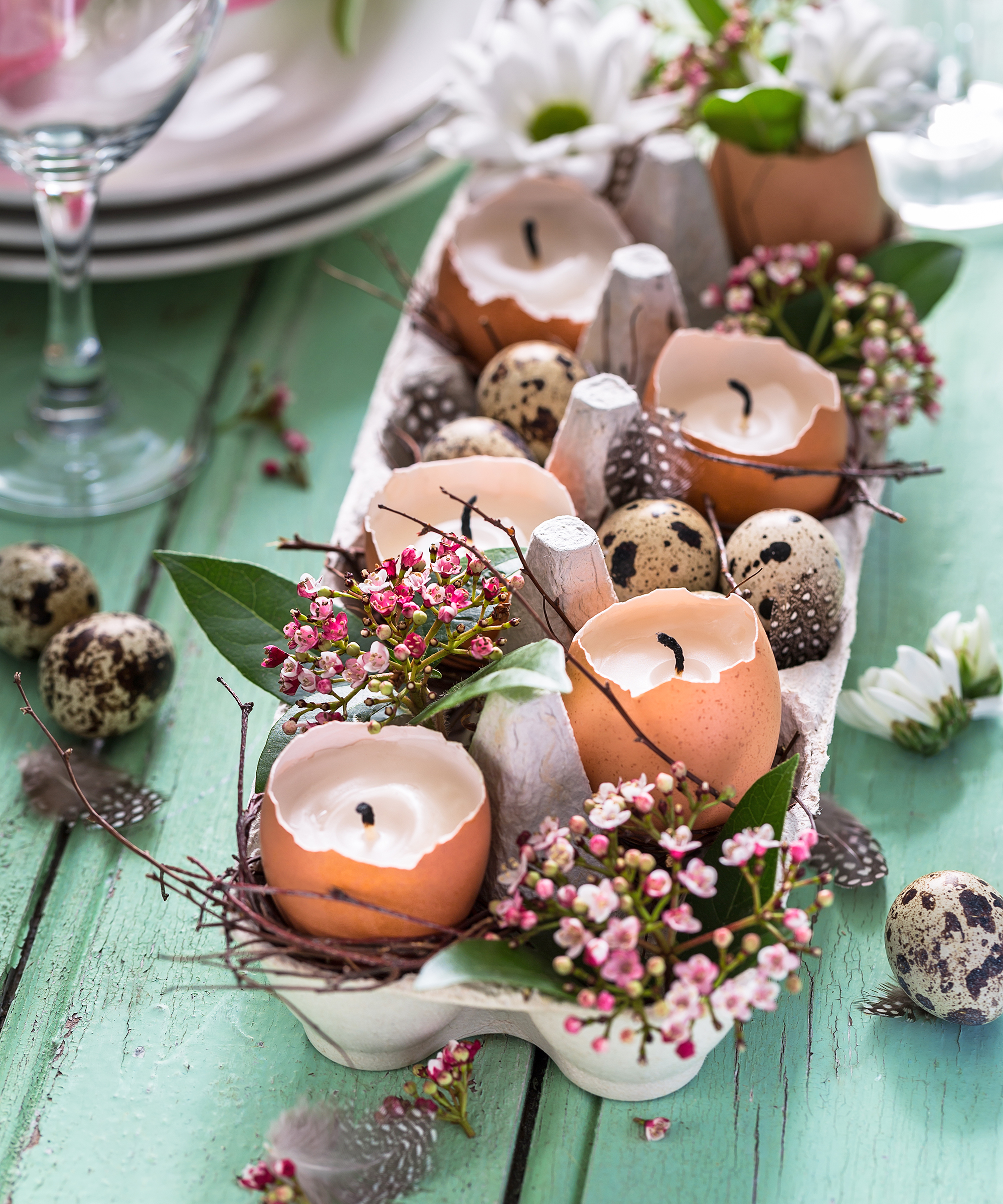 Egg carton filled with egg candles, flowers, and twigs