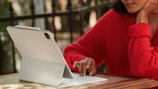 Best iPad keyboards: a woman using an iPad Pro with Apple's Magic Keyboard at a table outside 
