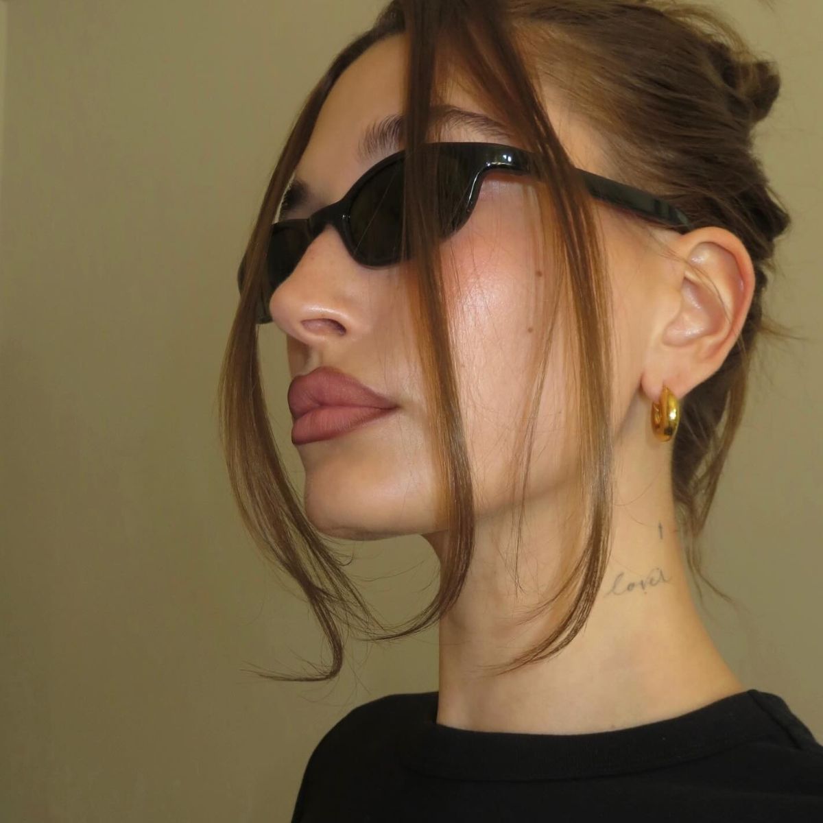 Hailey Bieber wearing a pair of black sunglasses with a chic updo hairstyle