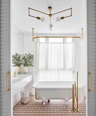 An example of bathroom lighting ideas showing lighting that matches the brassware and a tiled mosaic floor