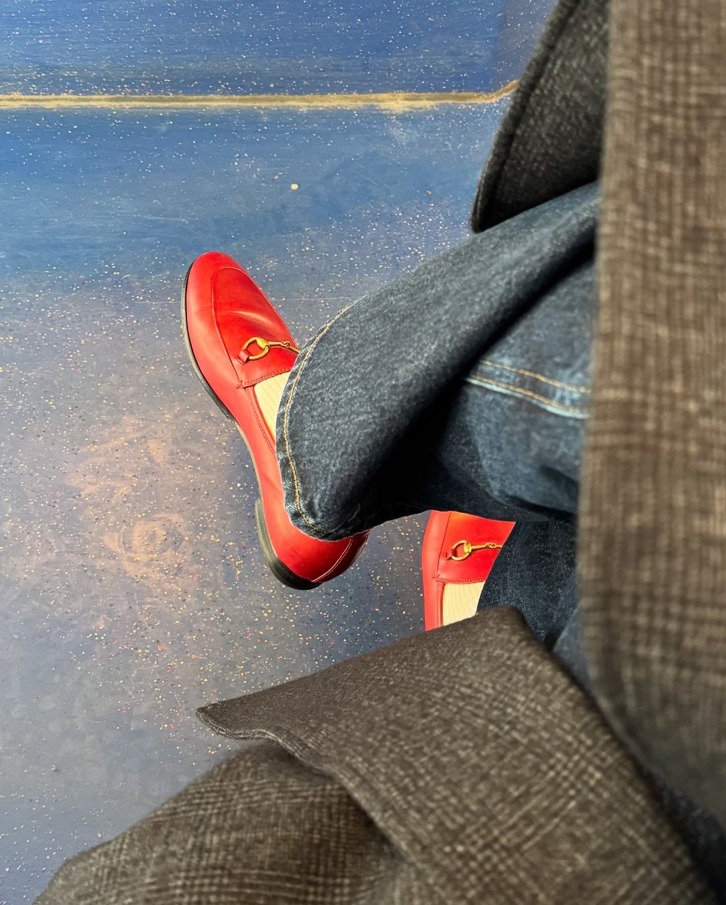 Photo of red Gucci loafers with butter yellow socks, dark straight jeans and a Tibi coat.