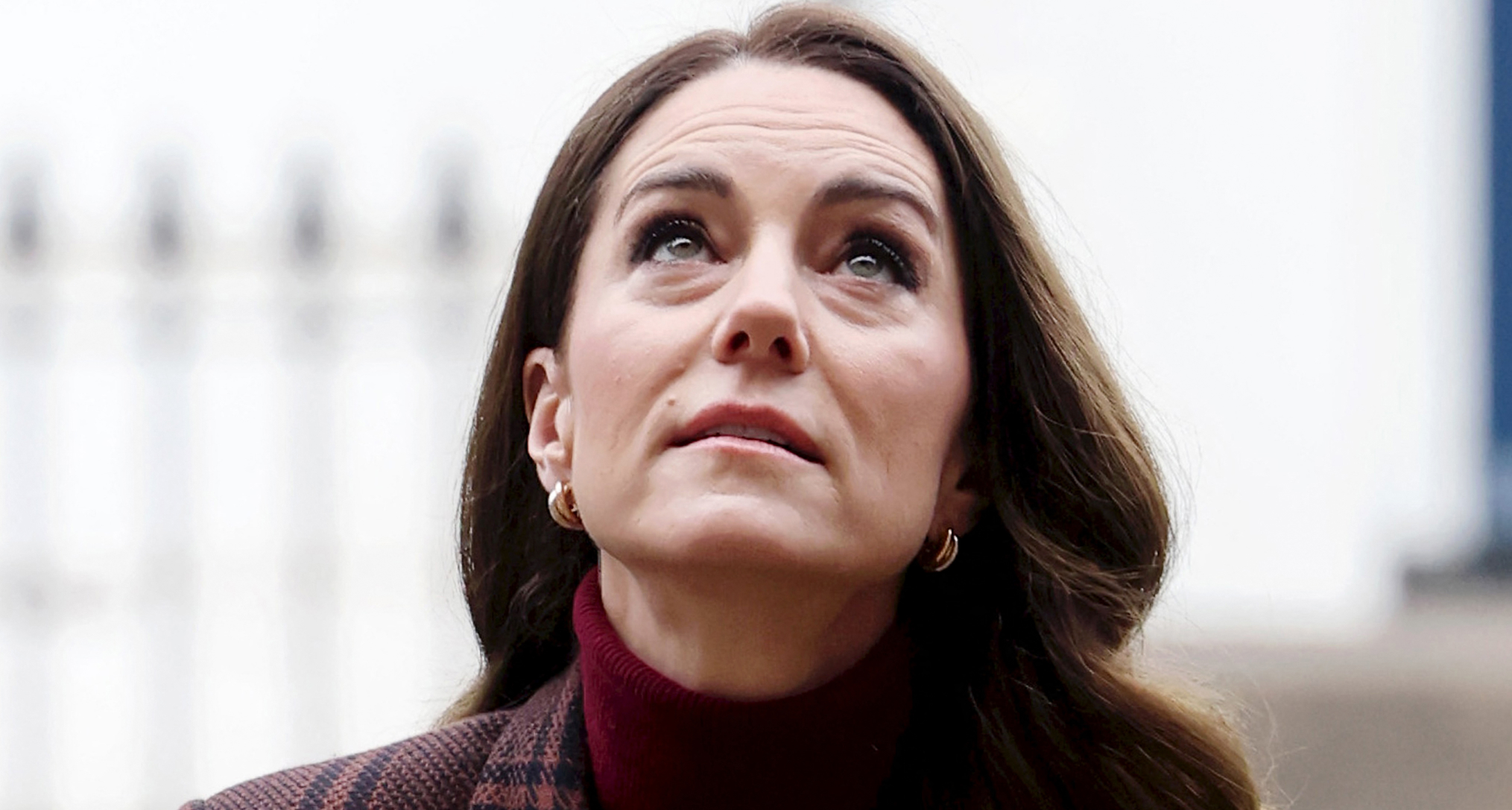 Princess Kate wearing a maroon sweater and coat looking up