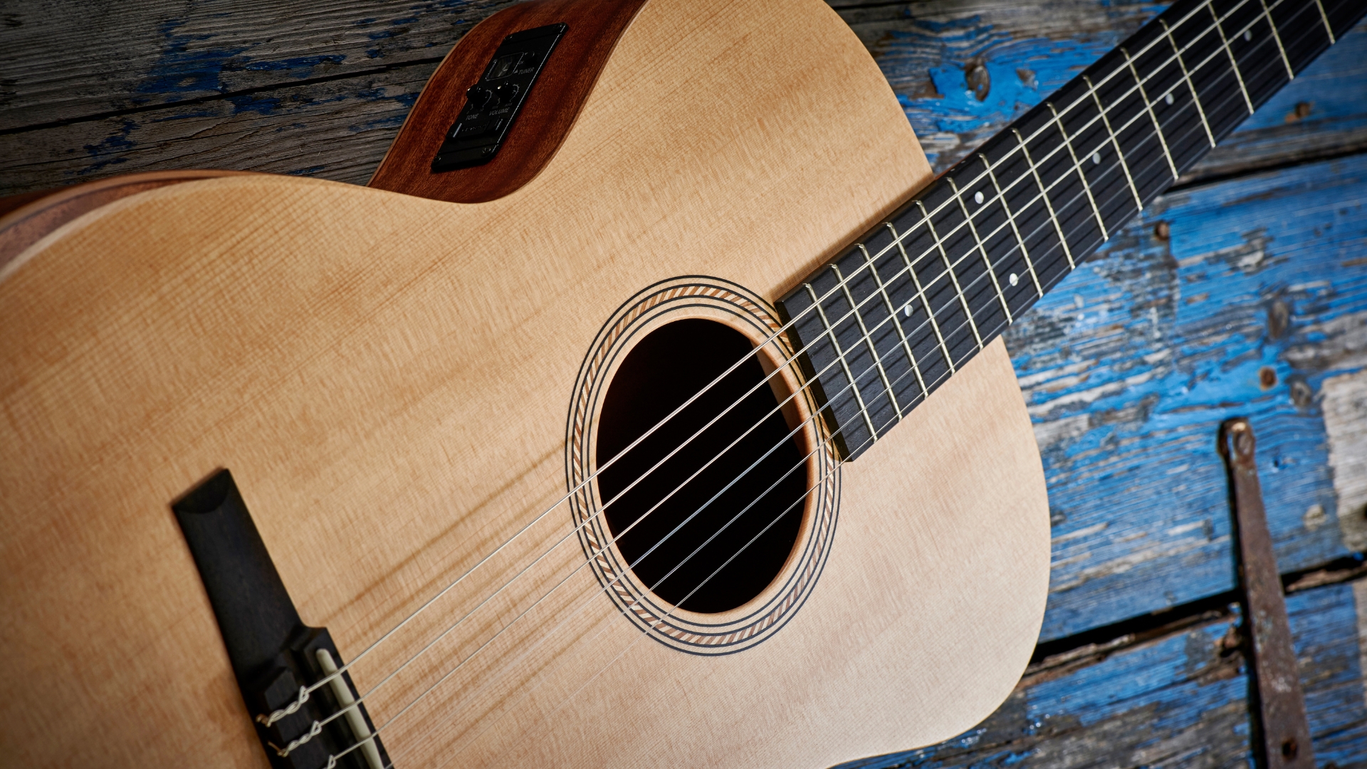 A Taylor Academy 12e-N classical guitar lying on a wooden floor