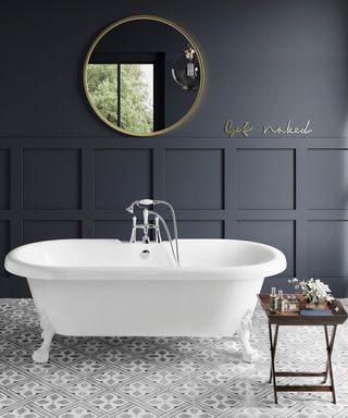 A dark blue bathroom with round bathroom mirror idea, white freestanding bath