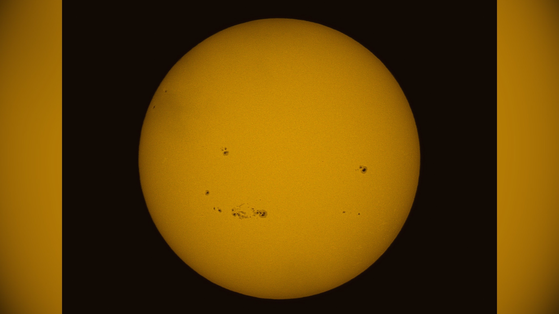 A close up view of the sun, there are large black spots visible - these are sunspots