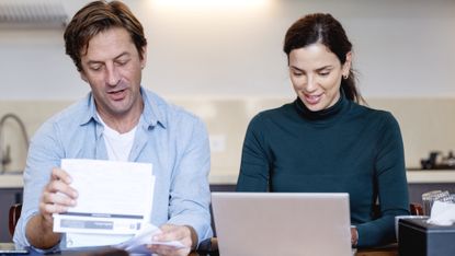 A couple work on financial planning together in their kitchen.