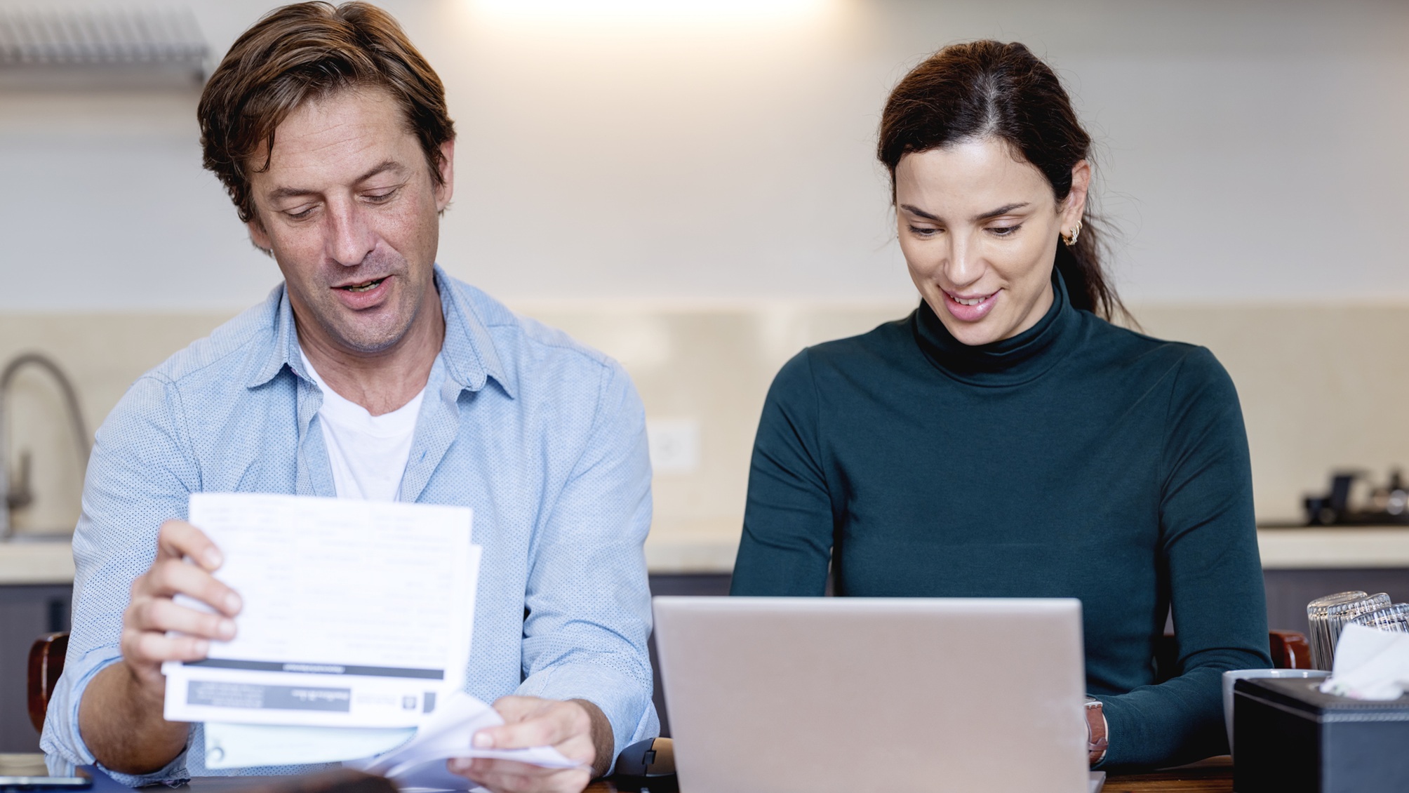A couple work on financial planning together in their kitchen.