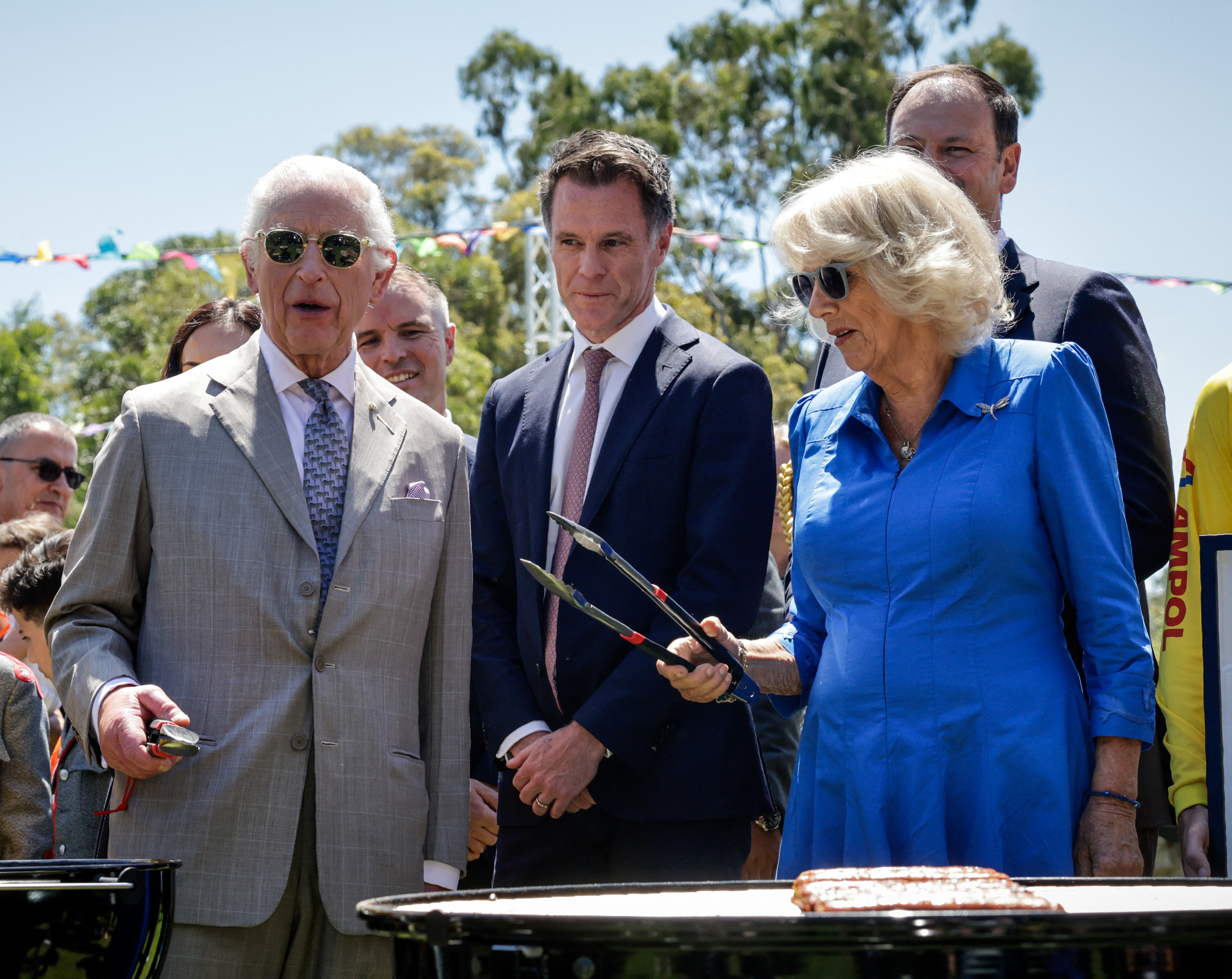 Britain's King Charles III and Queen Camilla (R) cook sausages as New South Wales Premier Chris Minns (2nd-R) looks on at the BBQ station as they attend the Premier's Community BBQ in Sydney on October 22, 2024. (Photo by Brook Mitchell / POOL / AFP) (Photo by BROOK MITCHELL/POOL/AFP via Getty Images)
