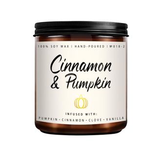 A dark brown candle jar with a beige label that says “Cinnamon and Pumpkin” in black letters