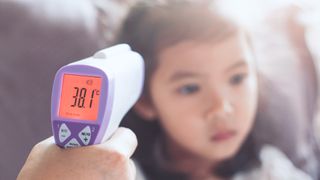 Mother taking her young daughter's temperature with a forehead thermometer