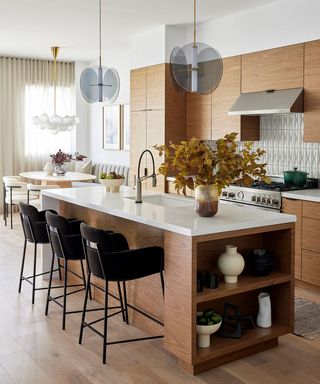 wooden kitchen with white work surface and kitchen island with bar chairs