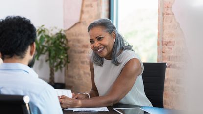A financial adviser smiles as she works with a client in her office.