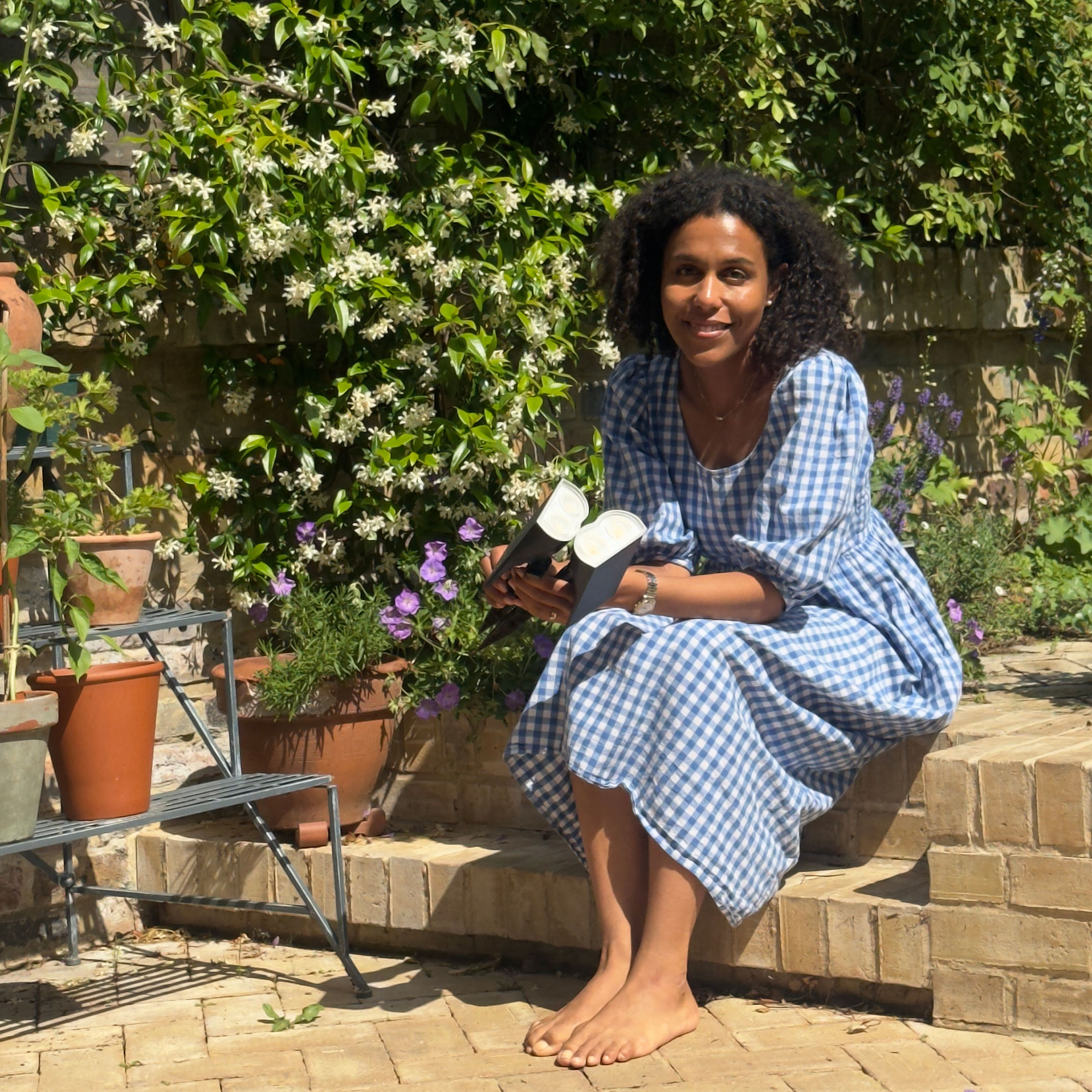 Woman in blue dress sitting on step in garden holding wireless lights