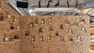 Liquor bottles sit on a tasting room wall with AtlasIED loudspeakers pumping in sweet tunes. 