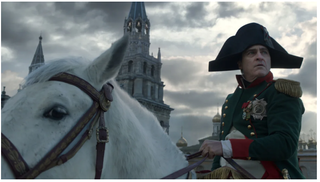  Joaquin Phoenix as Napoleon in full uniform sitting on a white horse