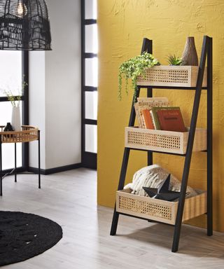 Black and rattan storage ladder with yellow wall