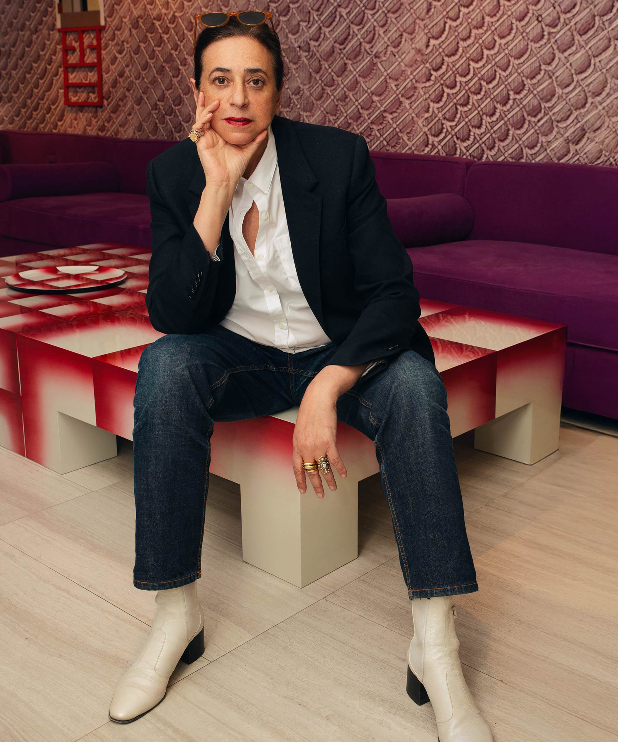 India Mahdavi sat on coffee table looking to camera