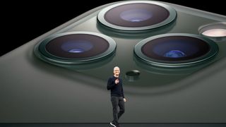 Tim Cook stood on stage in front of a slideshow showing a green iPhone 11