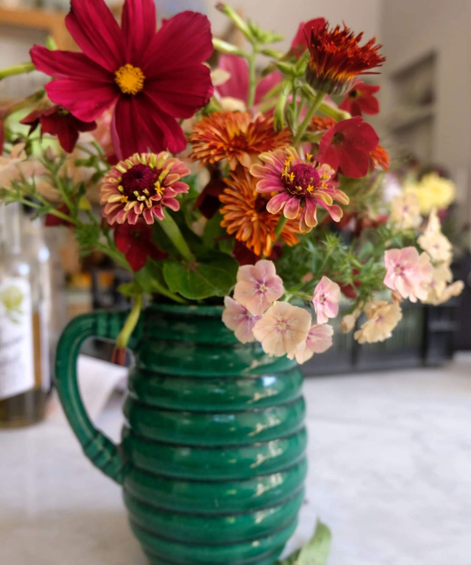 cosmos, dahlias and zinnias on green jug