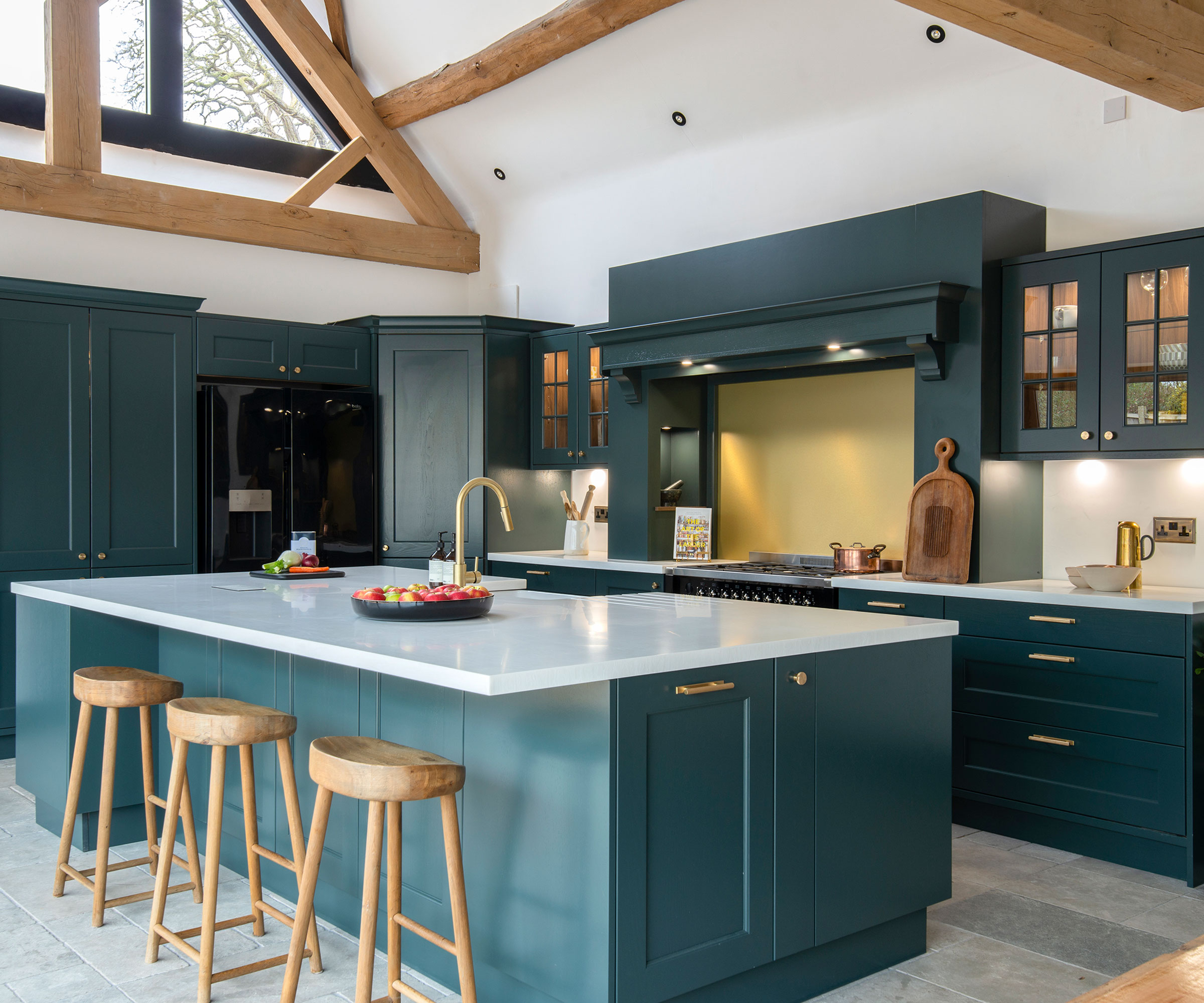 teal Shaker kitchen with white worktops and wooden bar stools
