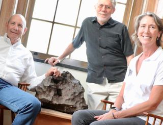 Drew Barringer (left), owner of Arizona meteor crater, his wife, Clare Schneider, and author William Herbst in the Van Vleck Observatory Library of Wesleyan University, where an iron meteorite from the crater is on display.