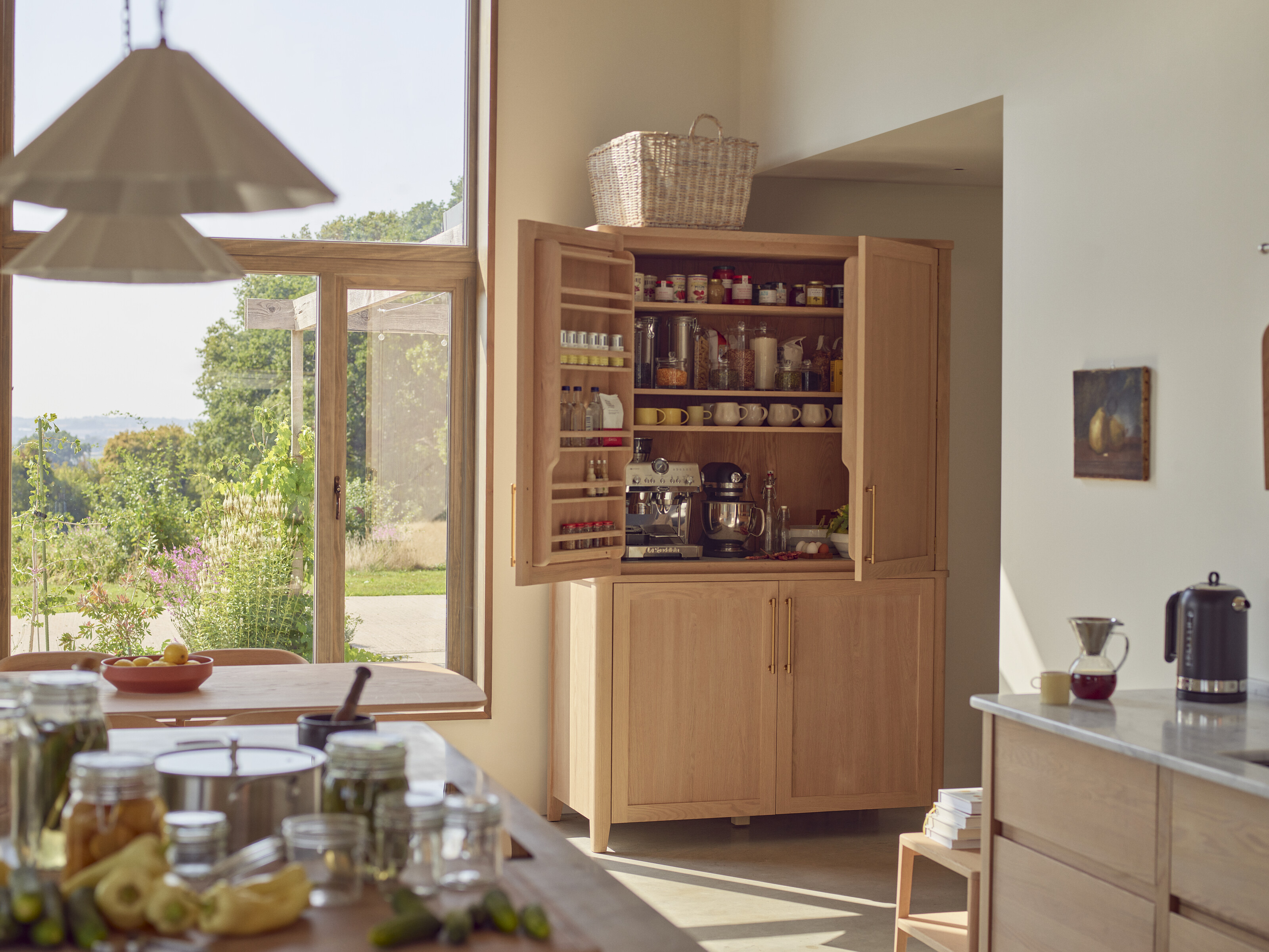 a pantry in a bright kitchen with windows overlooking nature