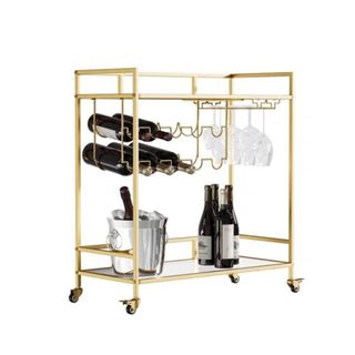 A gold two-tier rectangular bar cart with bottles of wine on the wine rack, glasses hanging from the holders, and wine bottles on the bottom tray