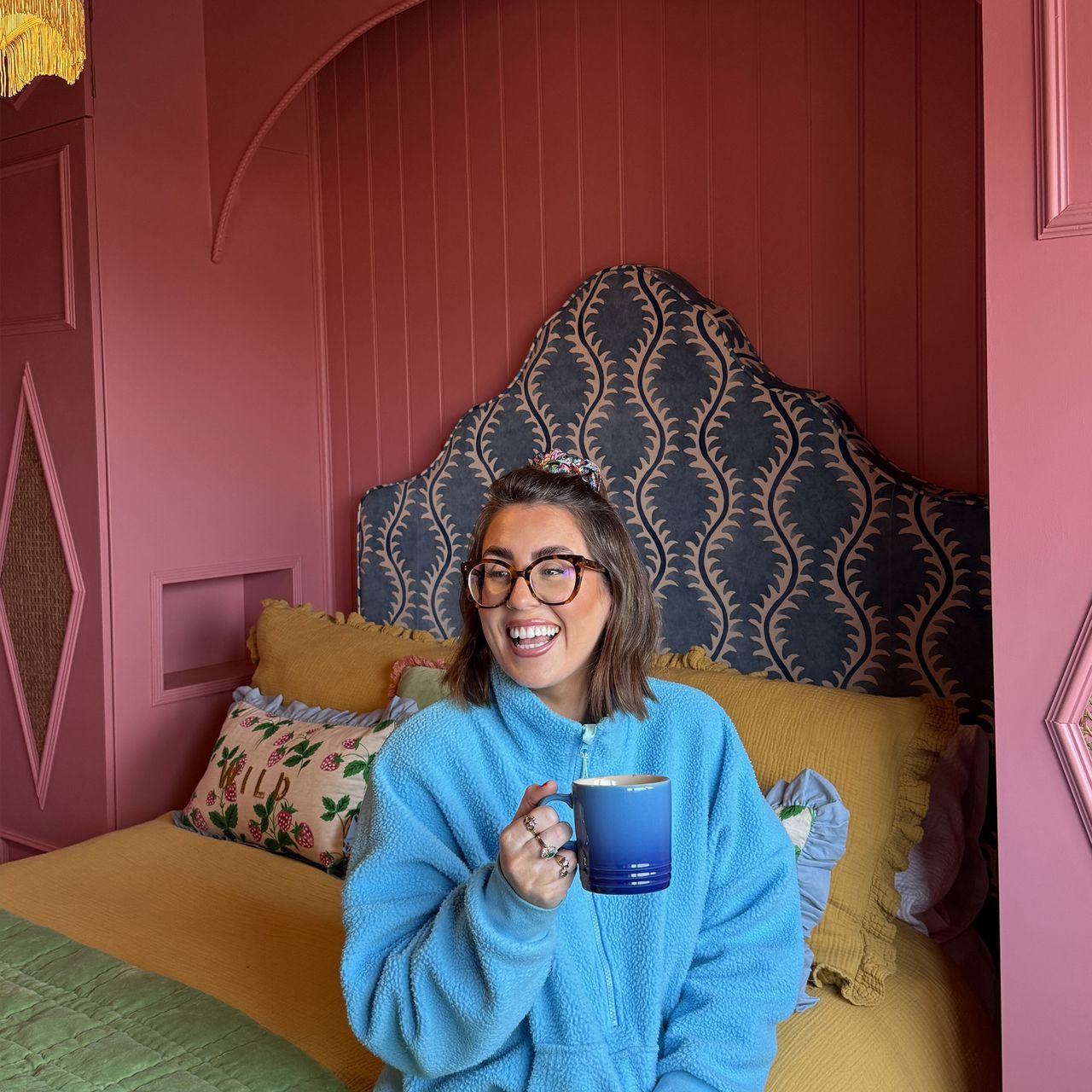 The dark pink bedroom of interior designer Roisin Quinn, with an upholstered ottoman bed from Button &amp; Sprung