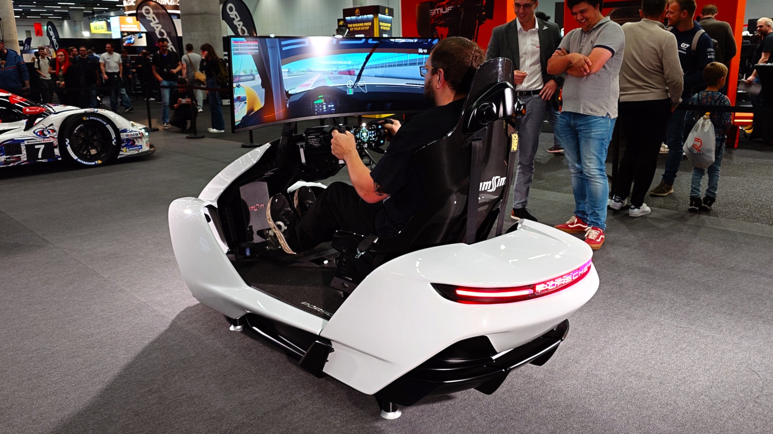 A photo of the ImSim Porsche Raceborn simulator in white showing glowing red Porsche lights on the rear.