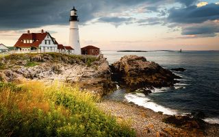 A lighthouse and building on the shore in Maine.