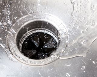 water running through a garbage waste disposal in a sink