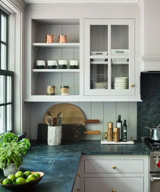 An off-white kitchen with soapstone countertops and gold hardware