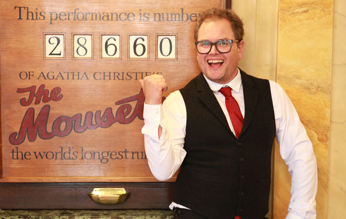 Alan Carr poses in front of a board for The Mousetrap.