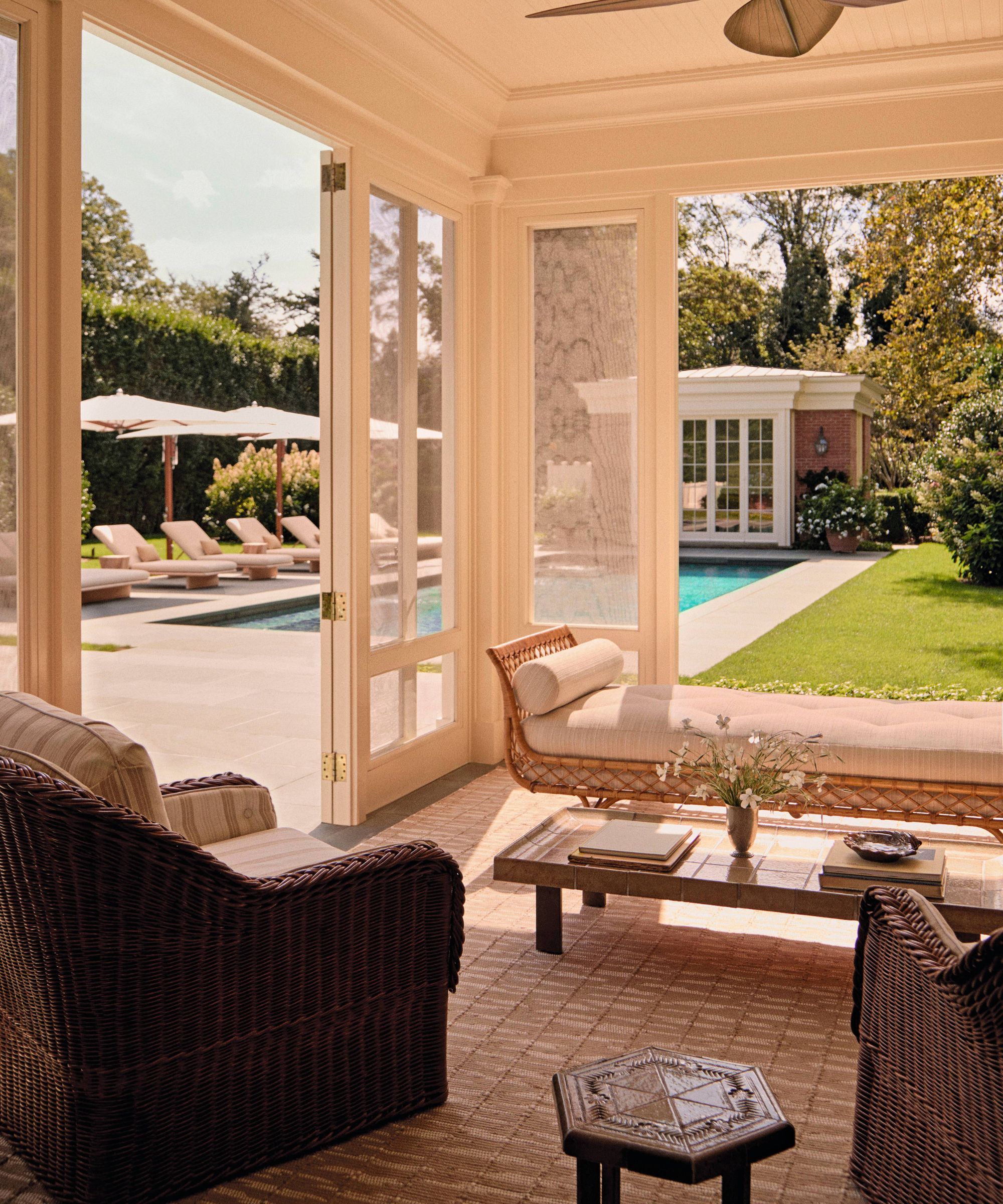 a bright sunroom opening up to a backyard in the hamptons with pool and pool house
